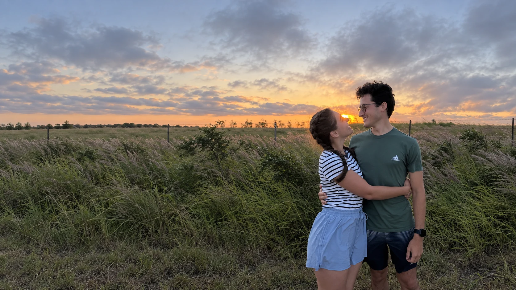 Gabriel and Rebecca embracing in a field at sunset.